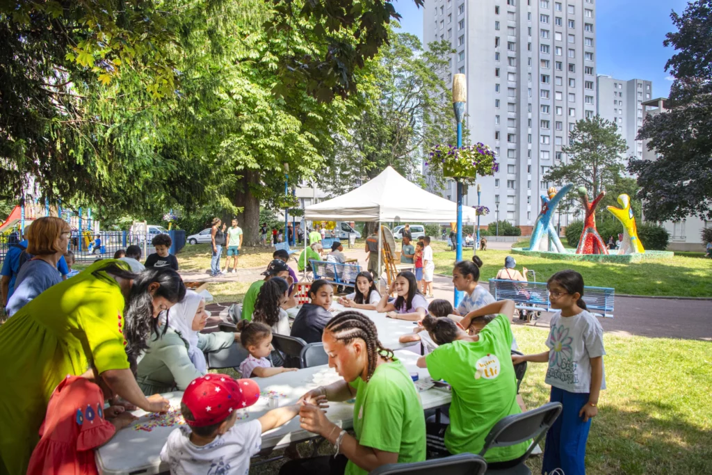 Des enfants et des parents participant à une activité artistique sous une tente blanche dans un parc.